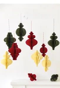 Christmas paper honeycomb pendants in red and green hanging on a white festive fireplace