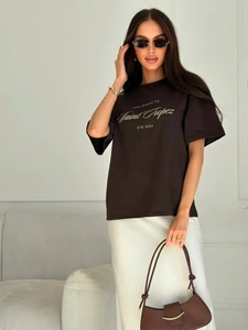 Detail of loose cotton T-shirt featuring gold artistic lettering and smooth cotton texture