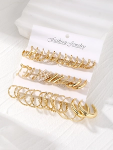 Close-up of 16-piece gold earring set with pearls and hoops on stone pedestal