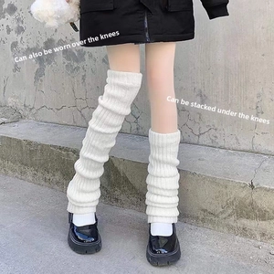 Detailed view of white cable knit leg warmers worn over knees with black platform shoes
