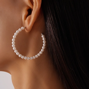 Close-up of model wearing large C-shaped earrings with white faux pearls on silver pins