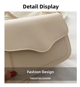 Detailed view of cream crossbody bag featuring curved flap design and fine stitching