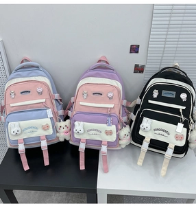 Three colorful student backpacks in blue, purple, and black with cute plush toy pendants