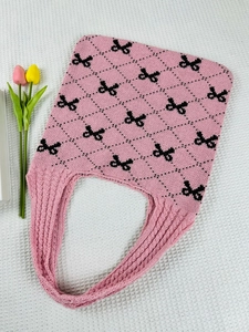 Detailed knit texture of pink tote bag featuring black bow patterns and diamond grid design