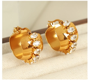 Detail of 18K gold plated wide C-shape huggie earrings with oval clear zircon stones