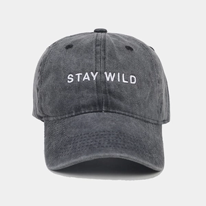 Close-up of white STAY WILD embroidery on a vintage washed dark grey cotton baseball cap