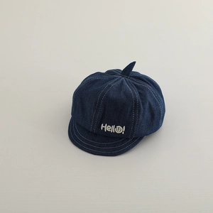 Close-up of kids denim newsboy hat with Hello embroidery and a playful top horn