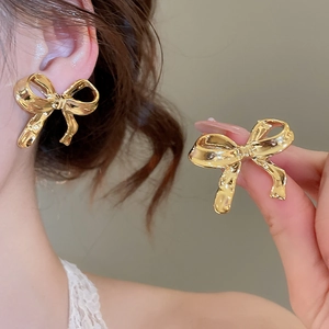 Gros plan détaillé de boucles d'oreilles nœuds dorés avec texture brillante et strass