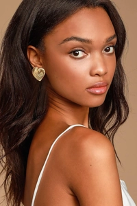 Close-up of golden irregular lava heart earring with textured surface on a model
