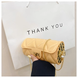 Close-up of beige quilted cylinder bag featuring gold chain and pearl decoration
