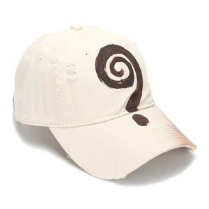 Dettaglio del cappellino beige effetto consumato con graffiti a spirale e bordi logori