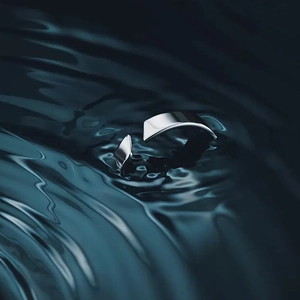 Macro shot of minimalist silver stainless steel open ring on wavy water surface