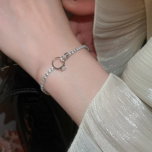 Close-up of sparkling zircon tennis bracelet with a miniature ring charm on a wrist