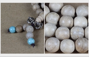 Macro detail of natural camphor wood beads with silver Vajra and turquoise accents