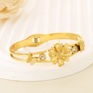 Bracelet jonc doré en acier inoxydable avec motifs marguerite et papillon sur fond blanc