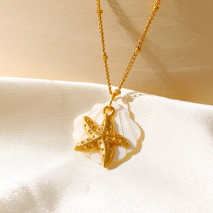 Détail du pendentif étoile de mer dorée avec coquillage blanc et chaîne à perles