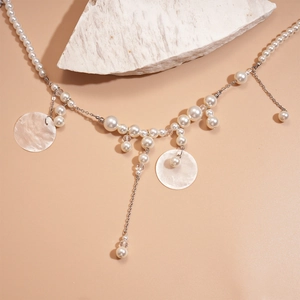 Detail of layered pearl necklace with shell pendant on a textured white stone base
