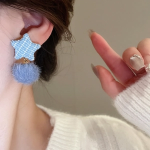 Detailansicht der Tweed-Ohrringe in Sternform mit blauen Plüsch-Pompons am Ohr