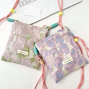 Detail of floral jacquard mini shoulder bag with adjustable pink strap and yellow cord lock