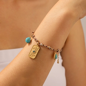 Detail of bohemian charm bracelet with celestial gold pendant and turquoise on model