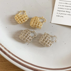 Macro detail of gold and silver hollow heart earrings on a ceramic dish with poetic card
