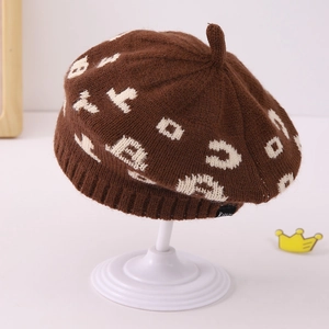 Detail of a brown jacquard knit beret with leopard pattern and ribbed edge on stand