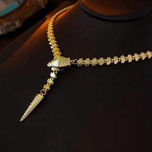 Macro shot of gold plated snake-style Y-shaped necklace with geometric scale texture
