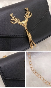 Detailed macro view of black PU leather bag with golden deer head and tassel chain