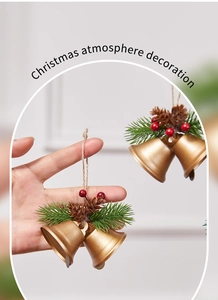 Close-up of gold Christmas bells with pine needles, red berries, and rustic twine