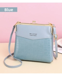 Detail of light blue kiss-lock shoulder bag featuring crocodile texture and gold hardware