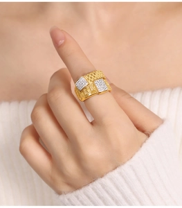 Close-up of a wide gold-plated twist ring with pavé diamond detail on a finger