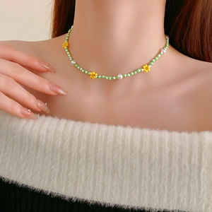Detail of beaded flower necklace with green seed beads and white pearls on a model neck