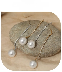 Detail of zircon and pearl tassel earrings in gold and silver finish on stone