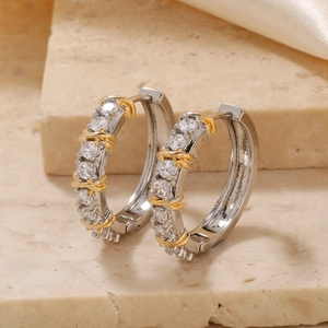 Elegant gold and silver two-tone hoop earrings with pavé cubic zirconia on stone background