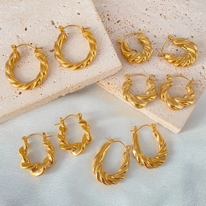 Macro shot of assorted gold-plated twisted croissant hoop earrings on stone display