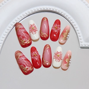 Elegant almond press-on nails with 3D floral accents and golden lines on cream base