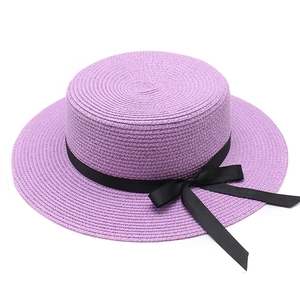 Détail d'un chapeau de paille violet à dessus plat avec un élégant ruban noir