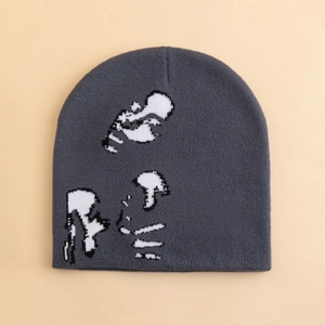 Dark grey knit beanie with pixelated abstract graphic on plain beige background