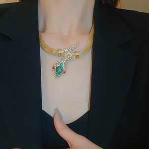 Detail shot of vintage gold snake necklace with green and red rhinestones on a model