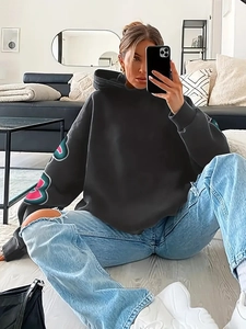 Detail of oversized dark grey hoodie featuring colorful letter print on sleeves