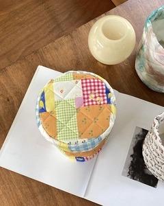 Close-up of a quilted patchwork storage bag with floral patterns on a wooden table