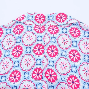 Detail of V-neck collar and vibrant geometric floral pattern on a smooth fabric blouse