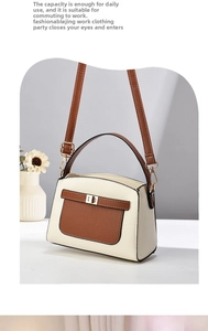 Detail view of contrast stitching and golden turn-lock on a two-tone leather handbag