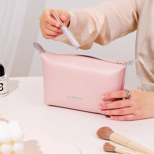 Pink PU leather makeup bag with heart LOVE print being filled with lip gloss