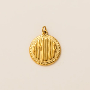 Macro detail of a 18k gold plated round pendant with embossed AMOUR lettering text