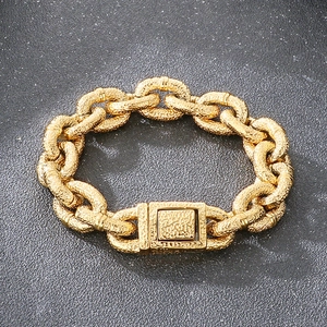 Close-up of golden heavy chain bracelet with hammered metal texture on dark background