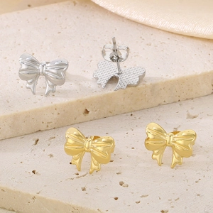 Gros plan de boucles d'oreilles nœud or et argent avec texture polie sur fond pierre