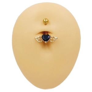 Détail du piercing de nombril cœur doré avec des ailes en zircon noir sur modèle