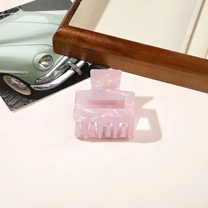 Detail of a pearlescent light pink square hair claw clip with a glossy shimmer finish