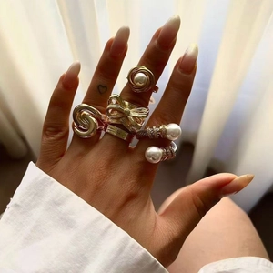 Gold stainless steel rings with pearl and butterfly accents on a hand model